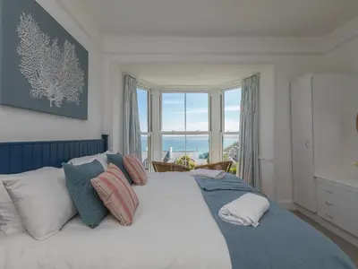 a bedroom with a large bed with a large window at 6 Albany Terrace in St Ives