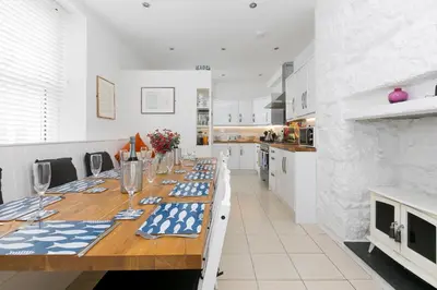 a kitchen with a long wooden table with blue and white decorations at 6 Albany Terrace in St Ives