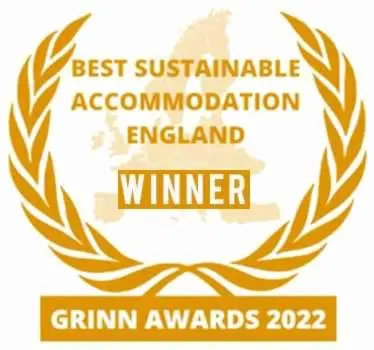 a gold laurelreath with the words best sustainable association england winner at The Paddock Wildcamp in Perranporth