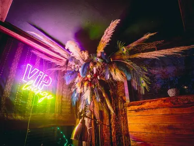 a palm tree in a room with a neon sign at The Paddock Wildcamp in Perranporth