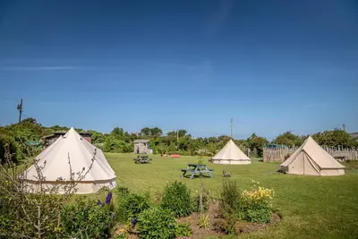 a group of tents sitting in a field at The Paddock Wildcamp in Perranporth