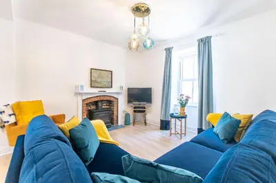 a living room with a blue couch and a fireplace at Picture House in St Ives