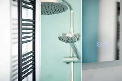 a shower head in a bathroom next to a mirror at Picture House in St Ives