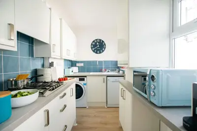 a kitchen with white cabinets and a clock on the wall at Picture House in St Ives