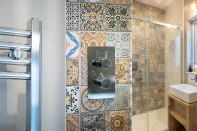 a bathroom with a shower with a tile wall at Primrose Cottage in St Ives