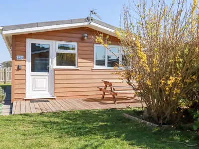 a wooden cabin with a bench on a deck at 224 Atlantic Bays in Padstow