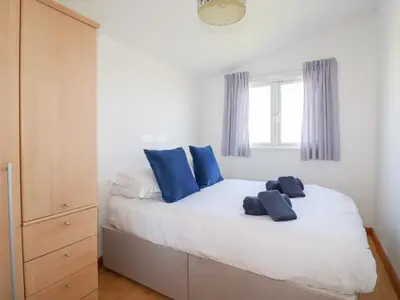 a bedroom with a white bed with blue pillows at 224 Atlantic Bays in Padstow