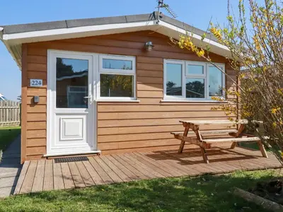a wooden cabin with a picnic table and a bench at 224 Atlantic Bays in Padstow