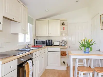 a white kitchen with white cabinets and a table at 224 Atlantic Bays in Padstow