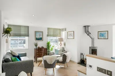 a living room with a couch and chairs and a fireplace at Harbour Master's House in Portreath