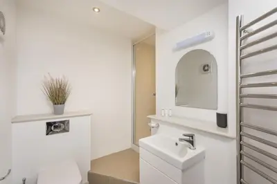 a white bathroom with a sink and a mirror at Harbour Master's House in Portreath