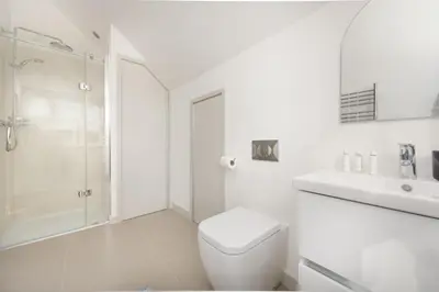 a white bathroom with a toilet and a shower at Harbour Master's House in Portreath