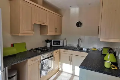 a kitchen with wooden cabinets and a stove top oven at The Honeypot - Cornish Apartment close to Eden Project & beaches in Par