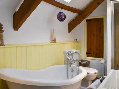 a bathroom with a bath tub and a toilet at Pineview Cottage in Downderry