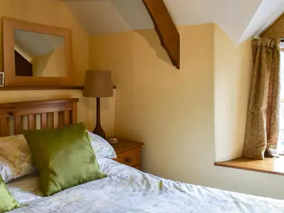 a bedroom with a bed and a mirror on the wall at Pineview Cottage in Downderry