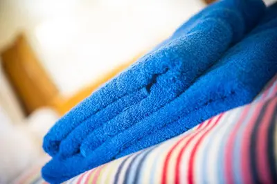 a blue towel sitting on top of a bed at Polrunny Farm Blackberry Cottage - Cornwall bliss in sight of the sea in Boscastle