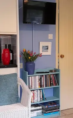 a living room with a book shelf filled with books at Blue Skies in St Ives
