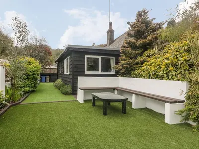 a garden with a bench and a house at By The Beach in Torpoint