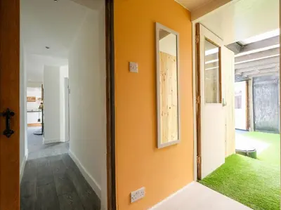 a hallway with an orange wall and a mirror at By The Beach in Torpoint