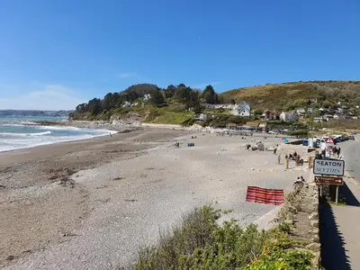 a beach with a bunch of people and the ocean at By The Beach in Torpoint