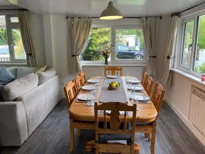a dining room with a table and chairs and a couch at By The Beach in Torpoint