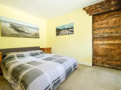 a bedroom with a bed and a wooden door at By The Beach in Torpoint