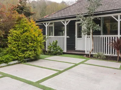 a house with a white fence and a yard at By The Beach in Torpoint