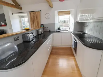 a kitchen with white cabinets and black counter tops at Little Chygowlin in Truro