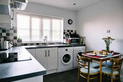 a kitchen with a washing machine and a table with chairs at Finest Retreats - Charnwood in Lewannick