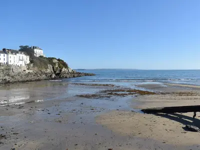 a sandy beach with houses and the ocean at Seatons Rest in Portmellon
