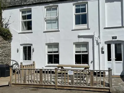 a white house with a picnic table in front of it at Seatons Rest in Portmellon