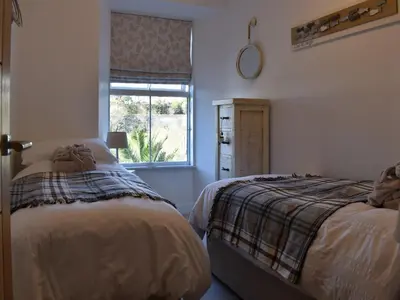 a bedroom with two beds and a window at Seatons Rest in Portmellon