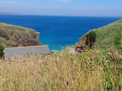 a car parked on a road next to the ocean at Farm accommodation - The Lizard Peninsula, Cornwall in Helston