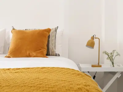 a bed with a yellow blanket and a table with a lamp at The Old Post Office in Helston