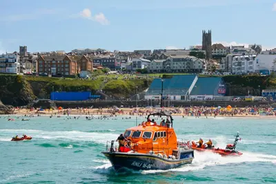 an orange boat in the water near a beach at Ollies 4 Cribbar in Newquay