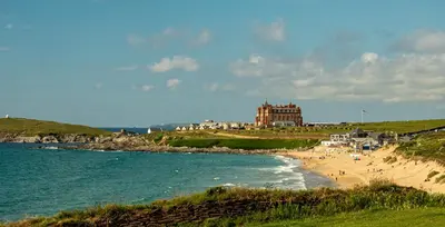 a beach with people on the sand and a building at Ollies 4 Cribbar in Newquay