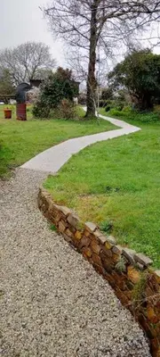 a stone path in a park next to a grass field at Trevenna Cabin in St Austell