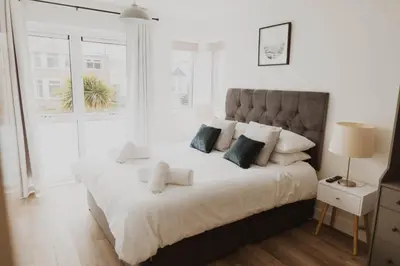 a white bedroom with a large white bed with pillows at Ocean 1- Sea View apartment, Fistral Beach Newquay in Newquay