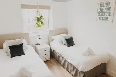 two beds in a room with white sheets and pillows at Ocean 1- Sea View apartment, Fistral Beach Newquay in Newquay