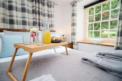 a bed with a table with a vase and flowers on it at The Cornish Nook Beautiful Grade 2 Listed Building In Cornwall By STAE-Homes in Camelford