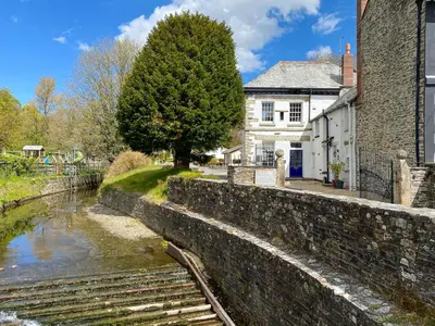 a stone wall next to a river in front of a house at The Cornish Nook Beautiful Grade 2 Listed Building In Cornwall By STAE-Homes in Camelford