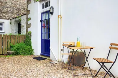 a table and chairs in front of a house with a blue door at The Cornish Nook Beautiful Grade 2 Listed Building In Cornwall By STAE-Homes in Camelford
