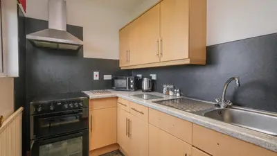 a kitchen with wooden cabinets and a sink and a stove at Boscastle View in Boscastle