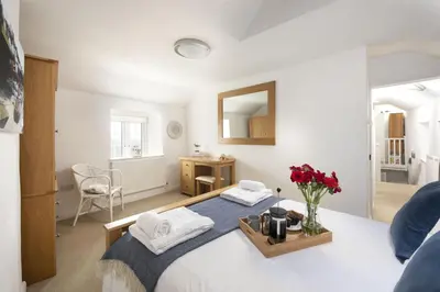 a bedroom with a bed with a vase of flowers at Dolor Cottage in Coverack