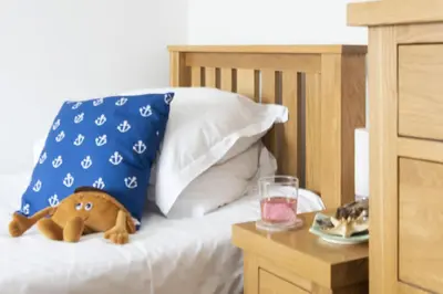 a stuffed animal sitting on a bed next to a pillow at Dolor Cottage in Coverack