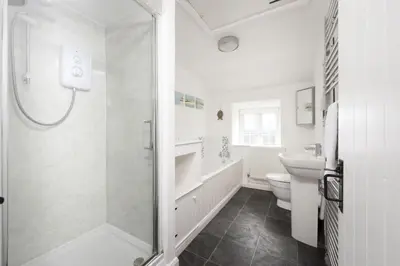a bathroom with a shower and a toilet and a sink at Dolor Cottage in Coverack