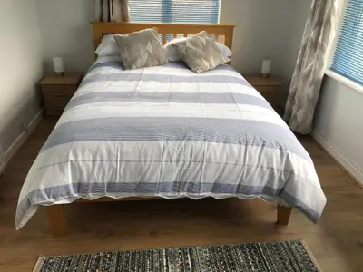 a bed with a blue and white comforter in a bedroom at SunnyVale Valley View Cottage in Gorran Haven