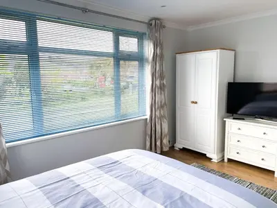 a bedroom with a bed and a flat screen tv at SunnyVale Valley View Cottage in Gorran Haven