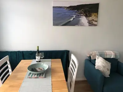 a dining room with a table and a blue couch at SunnyVale Valley View Cottage in Gorran Haven