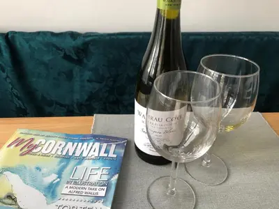 a bottle of wine and two glasses on a table at SunnyVale Valley View Cottage in Gorran Haven